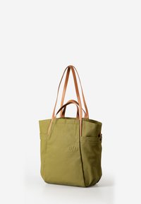 Olive green tote bag with tan leather handles, featuring stitched accents and two side pockets. Made of durable fabric, minimalistic design.