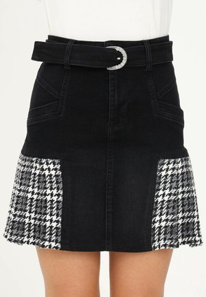 Schwarzer Jeansrock mit Fronttaschen, schwarzem Gürtel mit silberner Schnalle und seitlichen Hahnentrittmuster-Einsätzen nahe dem Saum.