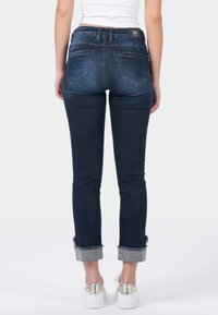 Donkerblauwe skinny jeans met een hoge taille en opgerolde mouwen, gemaakt van denim. Voorzien van twee achterzakken en een rafelranddetail.
