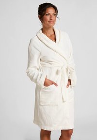 Beli kopalni plašč z vafljasto teksturo, dolgimi rokavi, šalovim ovratnikom in pasom na sredini. Vključuje dva sprednja žepa. Mehak, udoben material.