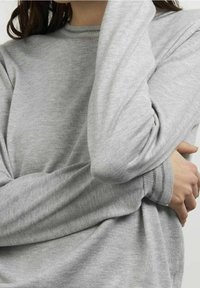 Grijze lange mouw top gemaakt van textuur gebreide stof, met een ronde halslijn en licht Gathered mouwen met subtiele accentstiksels.