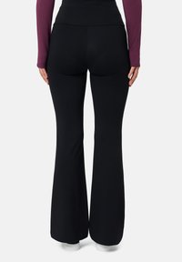 Černé rozšířené kalhoty z elastického materiálu, s vysokým pasem a hladkým, bez ozdobným povrchem.