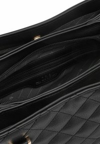 Intérieur de sac à main en cuir noir avec design matelassé, doté de plusieurs compartiments zippés et d'une étiquette de logo, texture lisse.