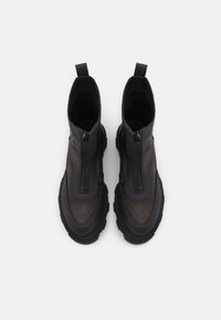 Botines negros con parte superior texturizada, doble cremallera, paneles laterales elásticos y suela de goma gruesa, con un acabado suave y tiradores.