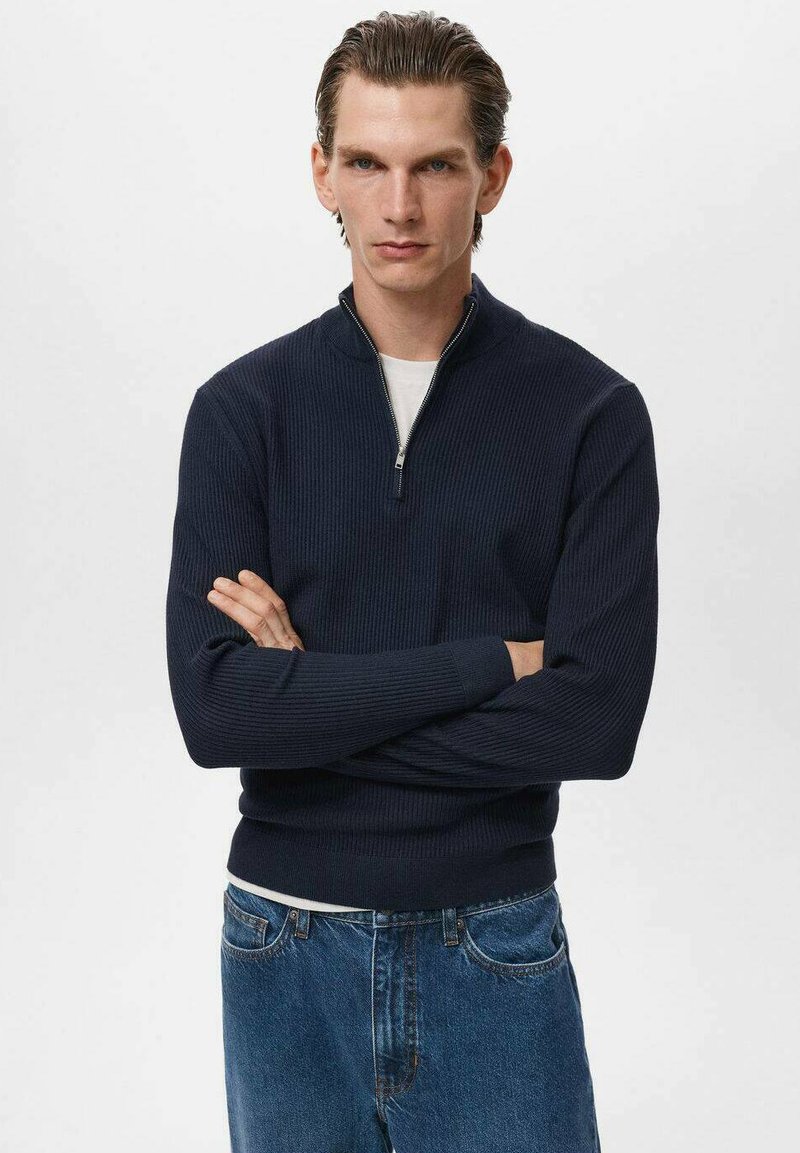 Pulover navy cu guler cu fermoar, textură côtă, mâneci lungi și siluetă ajustată, asortat cu blugi de culoare albastru deschis. Design casual și versatil.