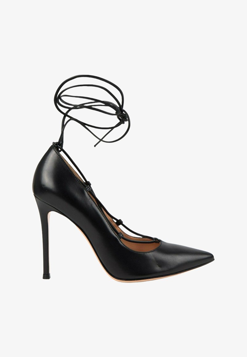 Chaussure à talon haut noire à bout pointu avec lacets enroulés autour de la cheville et talon aiguille fin, vue de profil sur fond blanc.