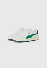 Witte sneakers met een groene zijkantstreep, voorzien van perforaties, gouden branding en een getextureerde rubberen zool. Minimalistisch ontwerp, vetersluiting.