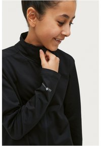 Zwarte zip-up jack met hoge kraag, gemaakt van gladde stof. Bevat nauwsluitende mouwen en een logo op de linkerpols.