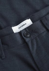 Pantaloni a quadri blu navy con texture liscia, dotati di etichetta GABBA e chiusura con bottone nero.