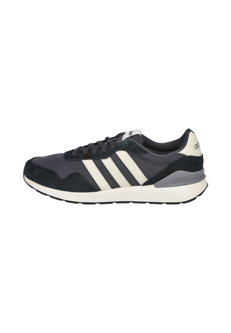 Zapatilla deportiva de azul marino oscuro con una combinación de materiales de ante y malla, tres rayas blancas, suela color crema y detalle gris en el talón.