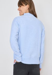 Hellblauer gestrickter Pullover mit hohem Kragen, langen Ärmeln und geripptem Saum. Verfügt über eine glatte Textur und ein nahtloses Design.