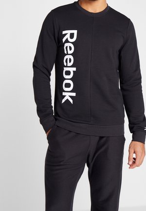 Felpa nera realizzata in morbido tessuto, con il logo bianco "Reebok" verticale sul lato sinistro, collo tondo e polsini a costine.