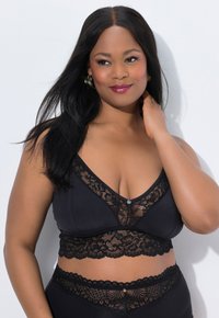 Černá podprsenka s hlubokým výstřihem do V, krajkovým lemem a zdobným knoflíkem. Obsahuje květinovou krajku podél okraje a podprsenkového pásu.