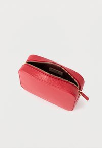 Piros bőr erszény texturált felülettel, arany cipzáras záródással, téglalap alakú és egy diszkrét márkajelzés belül.