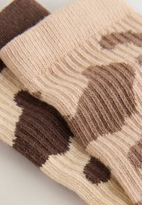 Calze di lana beige e marroni con grandi motivi a pois, texture a coste e orli ripiegati.