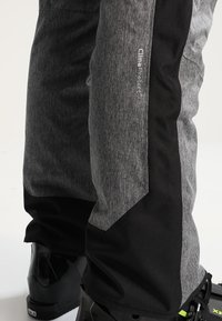 Pantalons de ski gris et noirs avec une finition texturée, arborant un logo 'Clima Protect' sur le côté. Conçus avec des zones renforcées pour plus de durabilité.