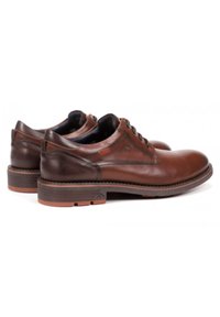 Zapatos de cuero marrón con un acabado suave, punta redondeada, diseño de cordones y tacón oscuro en contraste. Presenta costuras mínimas y suela de goma.