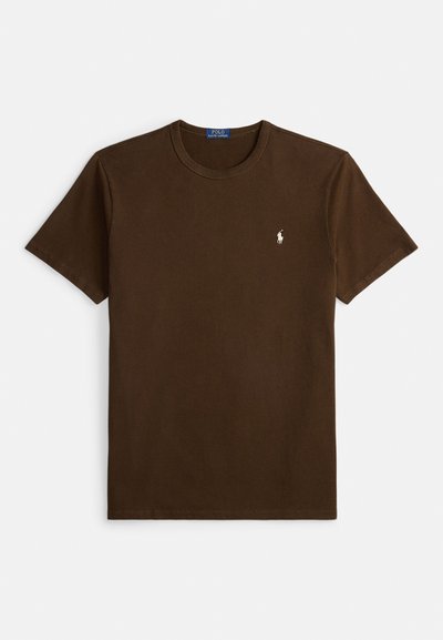 Brūna kokvilnas T-krekls ar apaļu kakla izgriezumu, īsām piedurknēm un nelielu baltu logo izšūtu uz krūtīm. Vienkāršs, viena krāsa dizains.