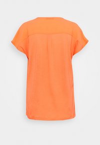 Haut orange à manches courtes avec une coupe ample, une texture lisse, un col arrondi et un détail de pli à l'arrière, conçu pour le confort.