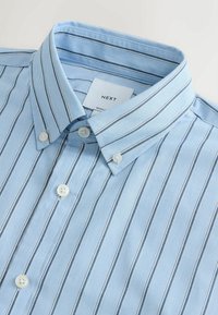 Sinine ja valge triibuline nööpidega särk klassikalise kraega, valgete nuppude ja kangatekstuuriga, mis näib sile ja krips.