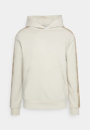 Off-white hooded sweatshirt with kangaroo pocket and beige stripes on sleeves printed with "Calvin Klein Jeans" text.