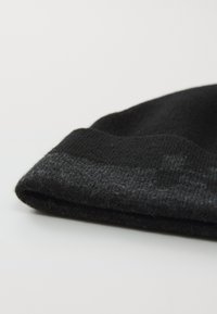 Zwarte gebreide beanie met een omslagrand, een gestructureerde ribbel en een verloop van zwart naar donkergrijs aan de rand van de omslag.