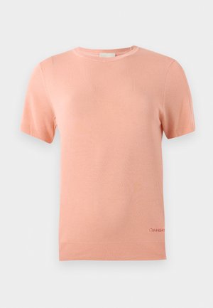 T-shirt de malha de manga curta em rosa claro com decote redondo e bainha canelada. Apresenta um pequeno logótipo da Calvin Klein na parte inferior.