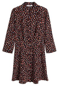 Robe noire à manches longues, avec une coupe ample, une ceinture à la taille et un motif de formes irrégulières rouges et blanches. Texture de tissu lisse.