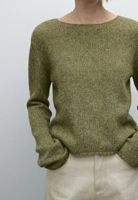 Olive green knitted sweater with long sleeves, wide neckline, ribbed texture, and a cropped hem, paired with light beige pants.