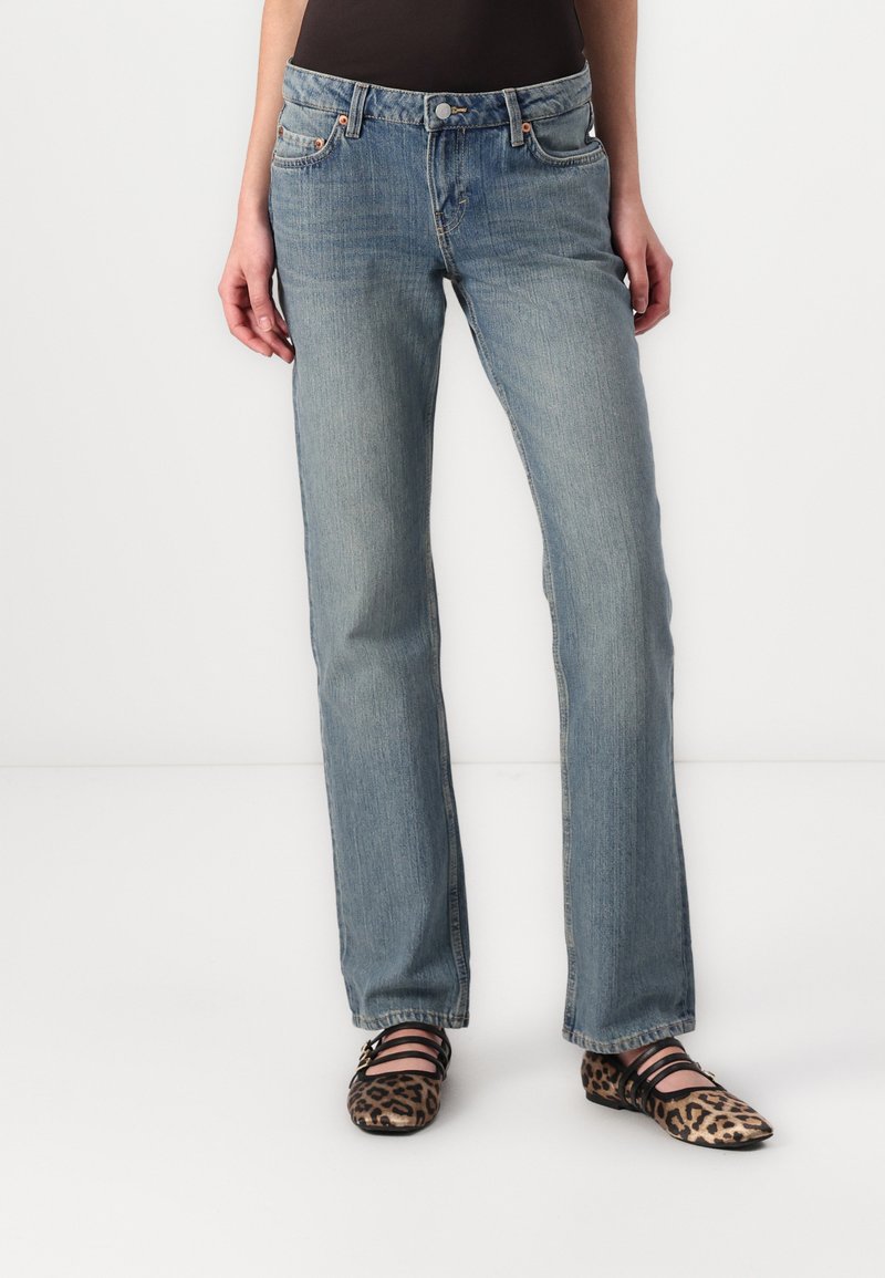 Jeans din denim albastru, drept, cu un finisaj decolorat, cinci buzunare și un sistem de închidere cu buton. Asortate cu pantofi plata cu imprimeu de leopard.