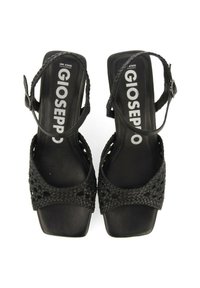 Sandalias negras con diseño superior trenzado y correa de tobillo ajustable. Forma de punta cuadrada y suela plana con la marca Gioseppo.