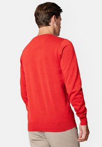 Czerwony sweter dziany z długimi rękawami, prążkowanymi mankietami i dołem, gładką fakturą oraz okrągłym dekoltem w dopasowanym fasonie.