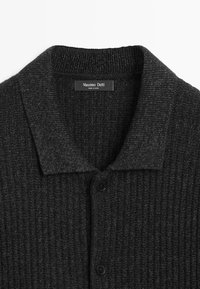 Dunkelgraue, gerippte Strickjacke mit einem umgeschlagenen Kragen, schwarzen Knöpfen und einem Etikett mit der Aufschrift "Massimo Dutti" in der Nähe des Halsausschnitts.