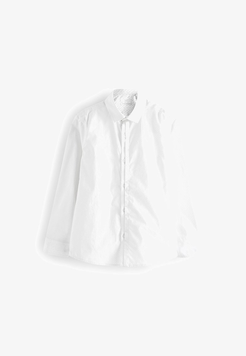 Chemise blanche à manches longues boutonnée avec un col pointu et un motif discret à pois à l’intérieur du col, étalée à plat sur un fond blanc.