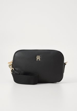 Sort syntetisk crossbody-taske med en glat tekstur, guldhardware, lynlås-lukning og en justerbar stofrem. Har et logo-accents.