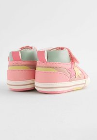 Chaussures pour enfants roses et vertes, avec un accent en étoile, bande Velcro, textures douces et semelle rayée multicolore.