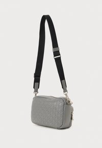 Grå crossover-taske i tekstureret læder, med diamantmønster, en justerbar sort rem og hardware i sølvfarve.