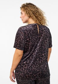 Haut noir avec un motif léopard, manches courtes et un détail en keyhole au dos. Fabriqué en tissu lisse et texturé.