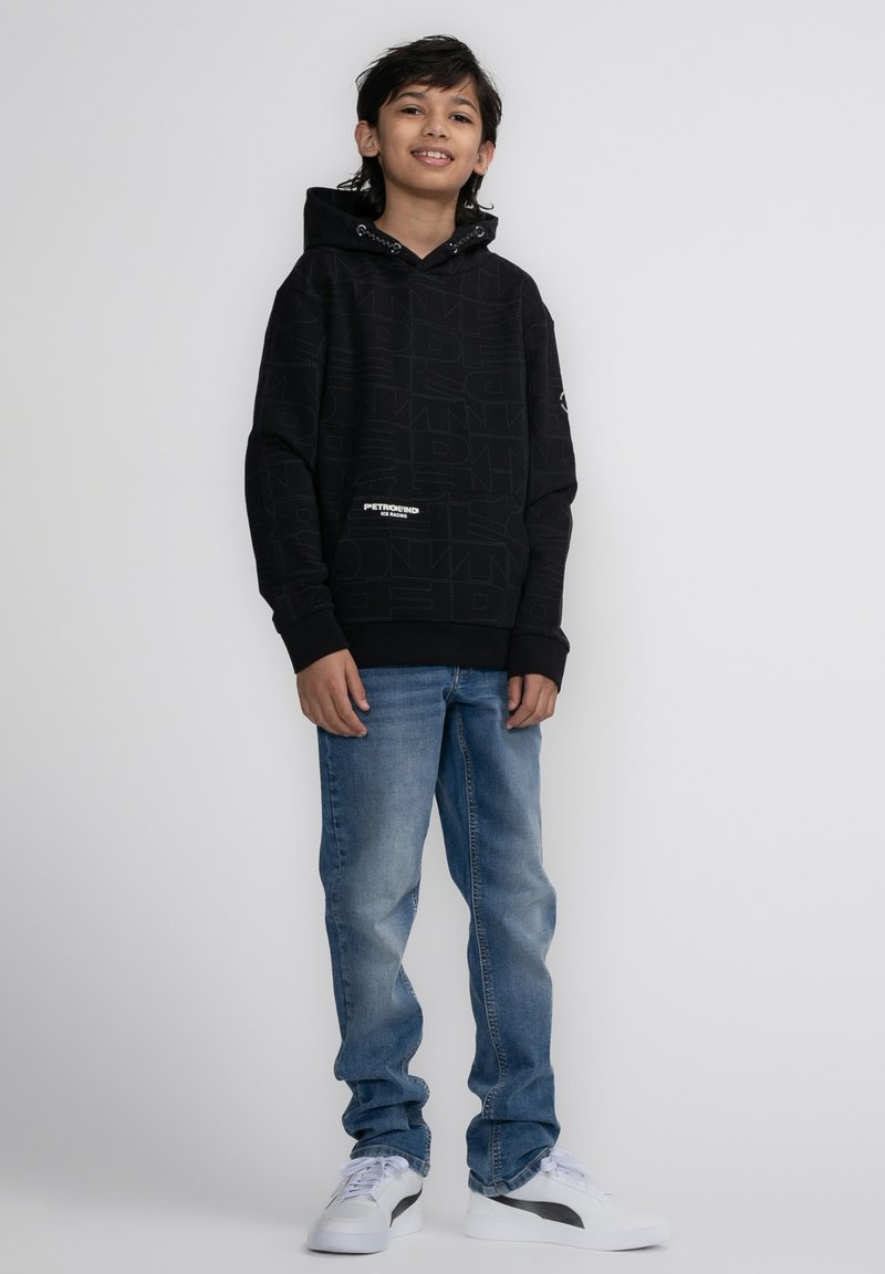 Felpa nera con cappuccio e motivo testuale in rilievo, tasca frontale, abbinata a jeans azzurri chiari e sneakers bianche. Design semplice e casual.