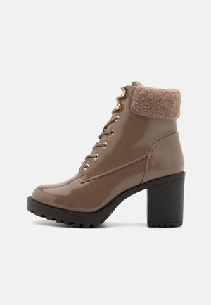 Bruine gepatineerde leren enkelboots met een gestructureerde bruine bontrand, gouden oogjes en een chunky zwarte hak. Rond neuspunt en robuole zool.