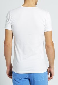 T-shirt bianco in cotone con maniche corte e scollatura tonda, caratterizzato da una texture liscia e un design aderente. Vista posteriore mostrata.
