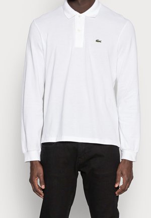 Langarm weißes Polohemd aus Baumwolle mit einer Drei-Knopf-Leiste und einem kleinen grünen Krokodil-Logo auf der linken Brust.