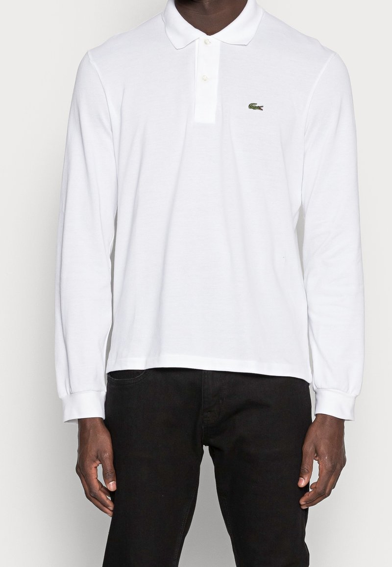 Witte poloshirt met lange mouwen gemaakt van katoen, met een drieknoopsluiting en een klein groen krokodillenlogo op de linkerkant van de borst.