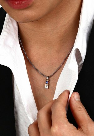 Silberne Kettenhalskette mit gestapeltem Anhänger, der einen blauen Stein, einen goldenen Akzent und einen rechteckigen silbernen Charme mit einem Muster enthält.