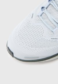 Αθλητικό παπούτσι σε ανοιχτό μπλε χρώμα με αναπνεύσιμο πλέγμα στο πάνω μέρος, υφή υφάσματος και κλείσιμο με κορδόνια. Διαθέτει λαστιχένια σόλα και διακριτικές λεπτομέρειες.