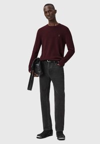 Maglione a maglia bordeaux, jeans in denimm neri, borsa nera con finitura testurizzata e stivali neri con accenti argento. Outfit semplice e moderno.