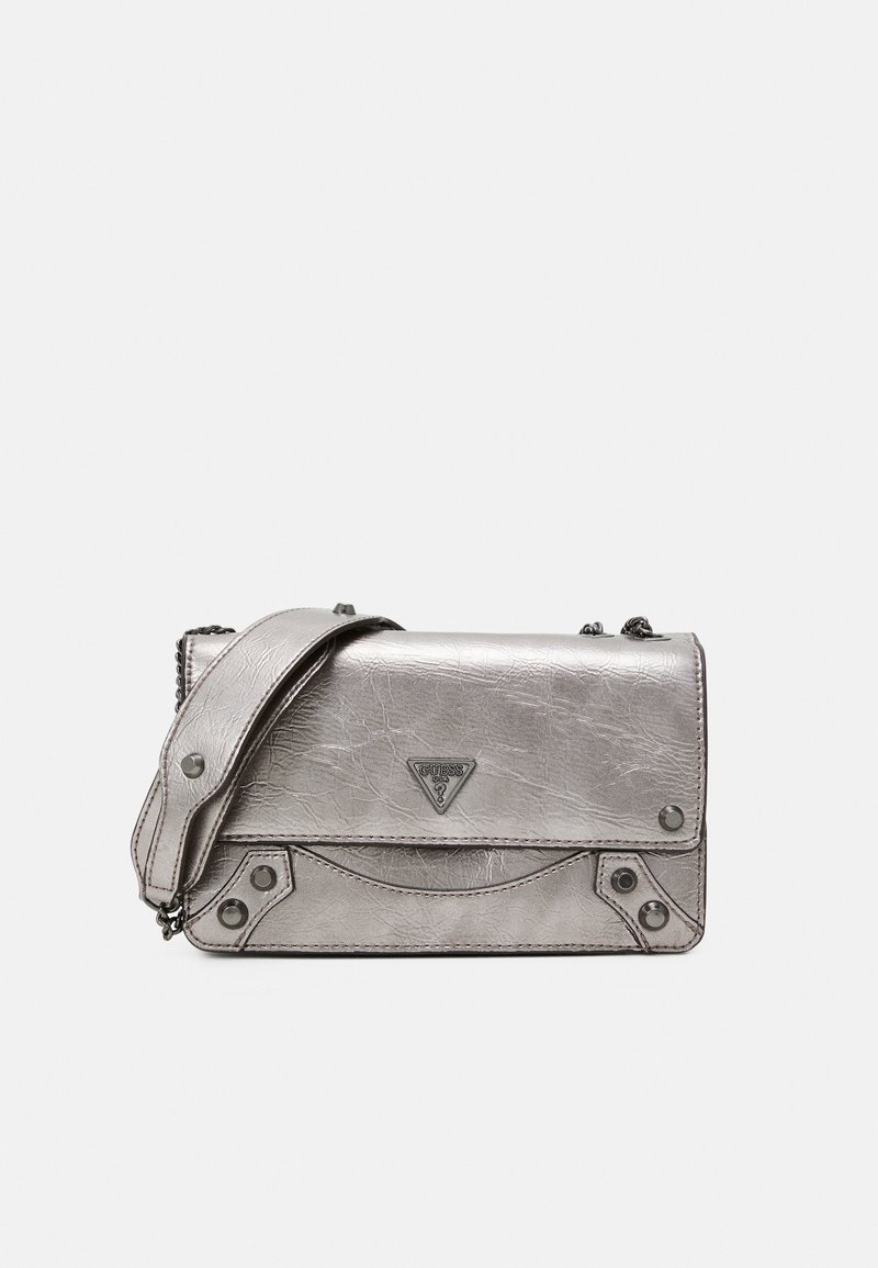 Petit sac à bandoulière en cuir argenté avec bandoulière chaîne, clous métalliques et logo Guess triangulaire sur le rabat avant.
