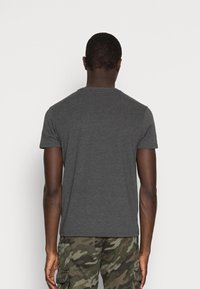 Gray short-sleeve t-shirt with a crew neckline and smooth texture, worn with camouflage cargo pants, shown from the back.