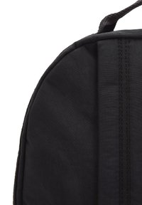 Zaino in tessuto nero con angoli, superficie texture, forma arrotondata e cuciture rinforzate lungo i bordi. Design semplice, senza hardware visibile.