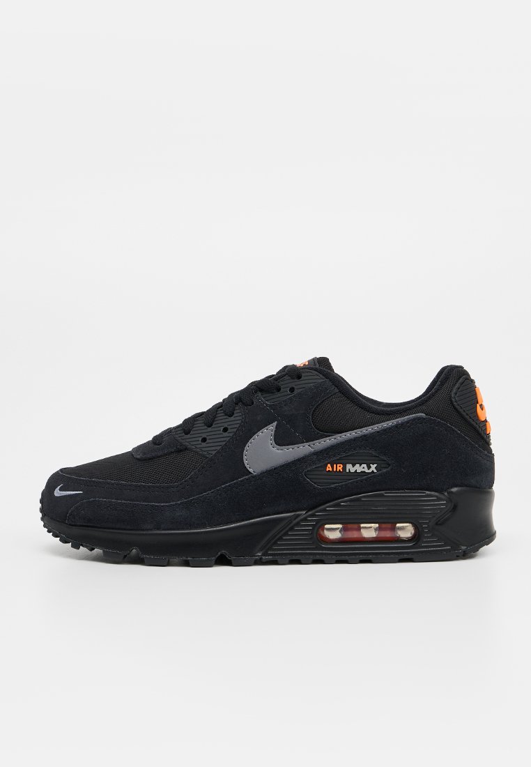 Baskets Nike Air Max noires avec un swoosh gris, une semelle intercalaire visible à coussins d'air, et des accents orange "Air Max" et logo, vue latérale sur fond blanc.